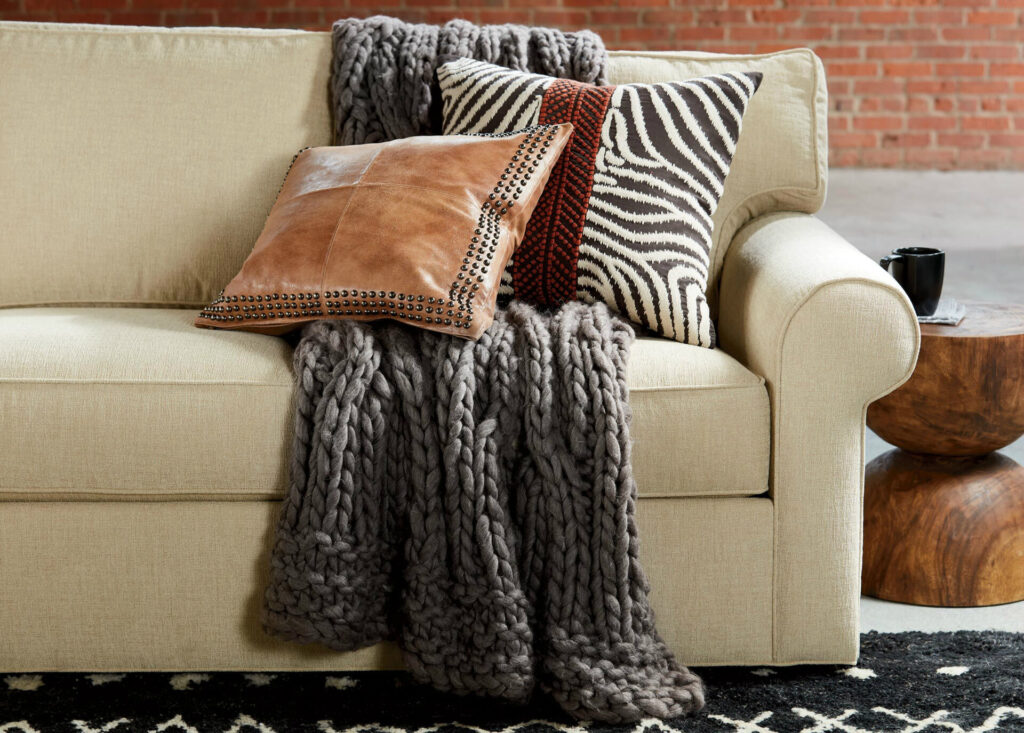 Eine Alpaka Decke liegt zusammen mit Kissen auf Sofa