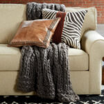 Eine Alpaka Decke liegt zusammen mit Kissen auf Sofa