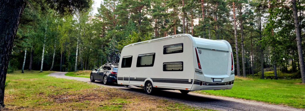 Auto mit Camping-Anhänger im Wald