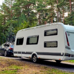 Auto mit Camping-Anhänger im Wald